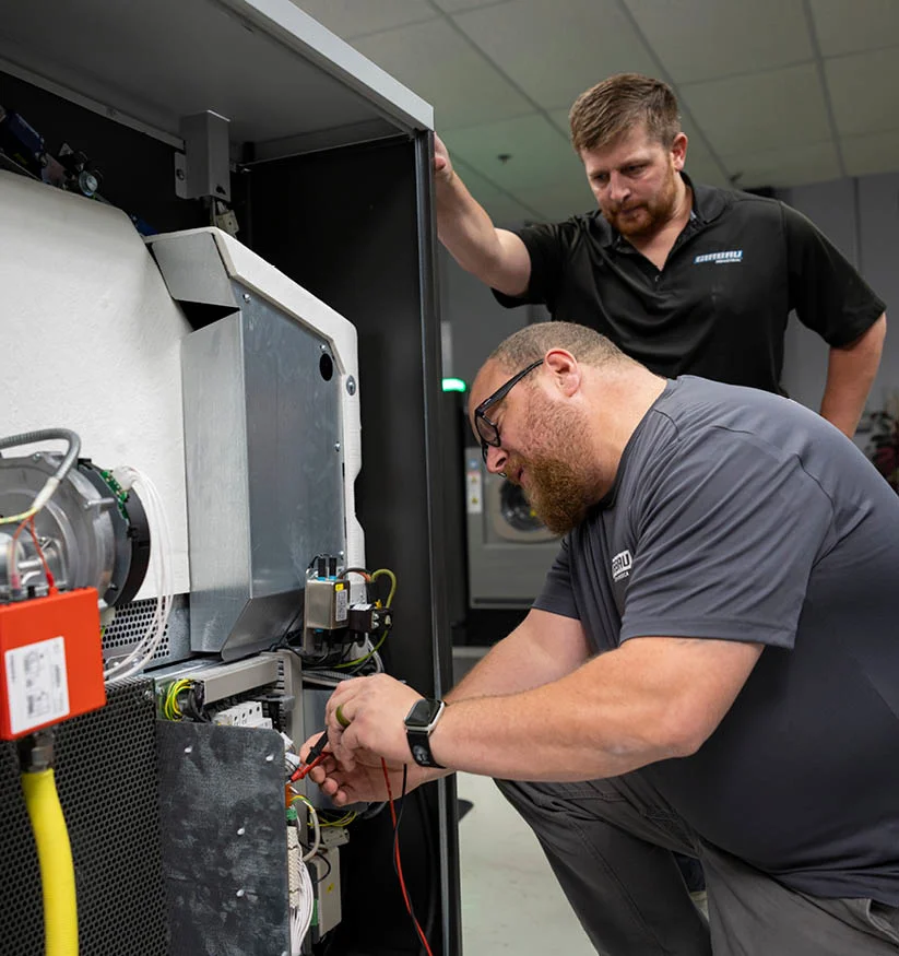 Aqualogic technicians testing and repairing the electrical components of a Girbau machine during an urgent repair