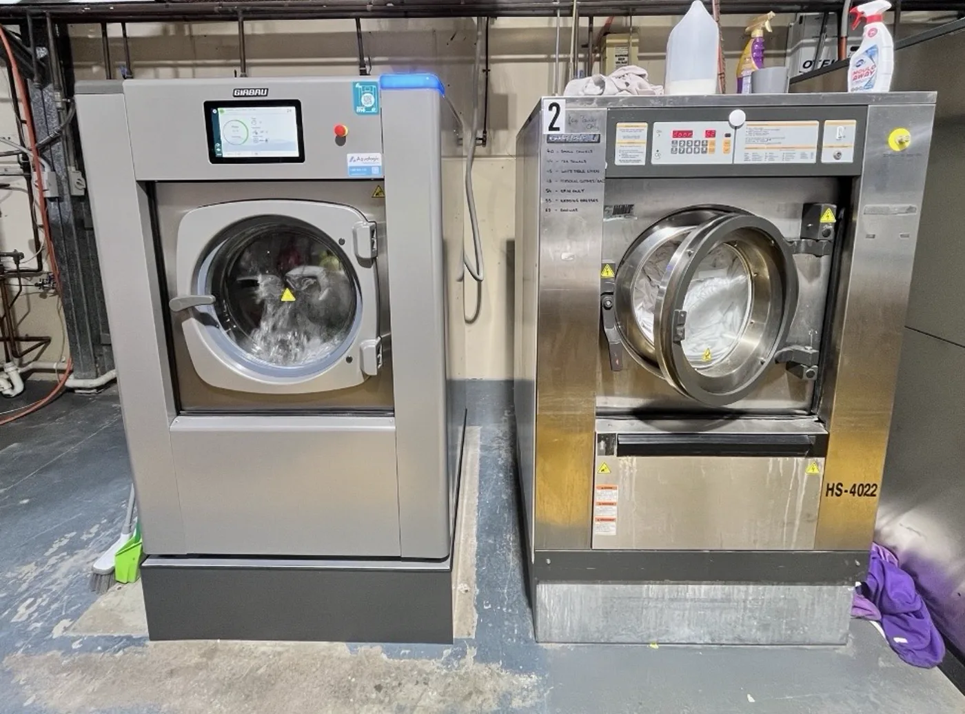A Girbau front load washer and an IPSO washer extractor side by side in a site laundry