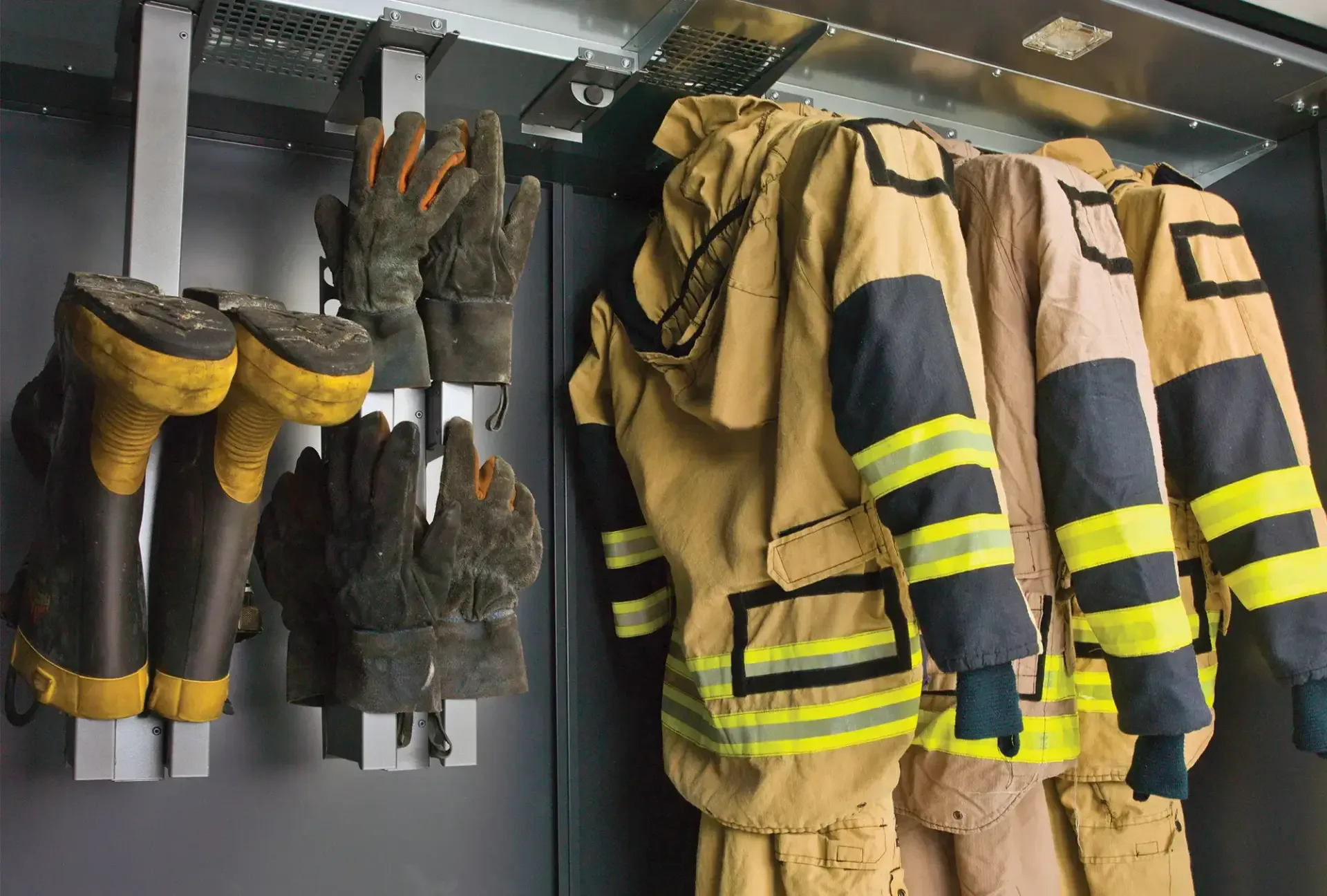 Turnout coats, gloves and boots drying on rails inside a commercial drying cabinet